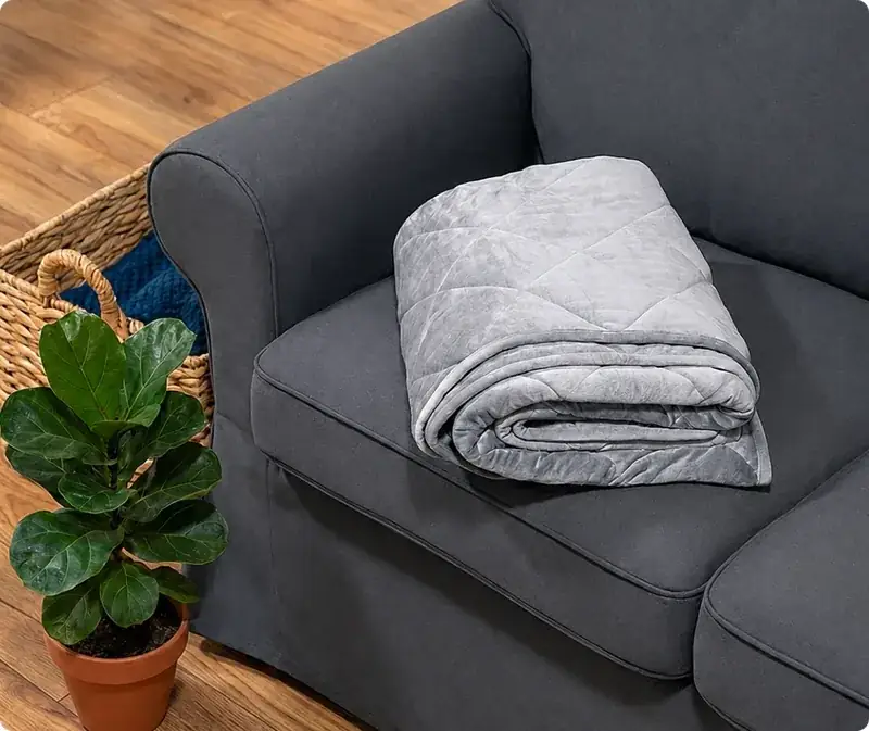 Velin Weighted Blanket folded on a dark grey sofa in a living room