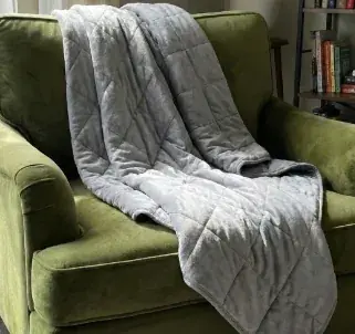 Velin Weighted Blanket draped over a green armchair